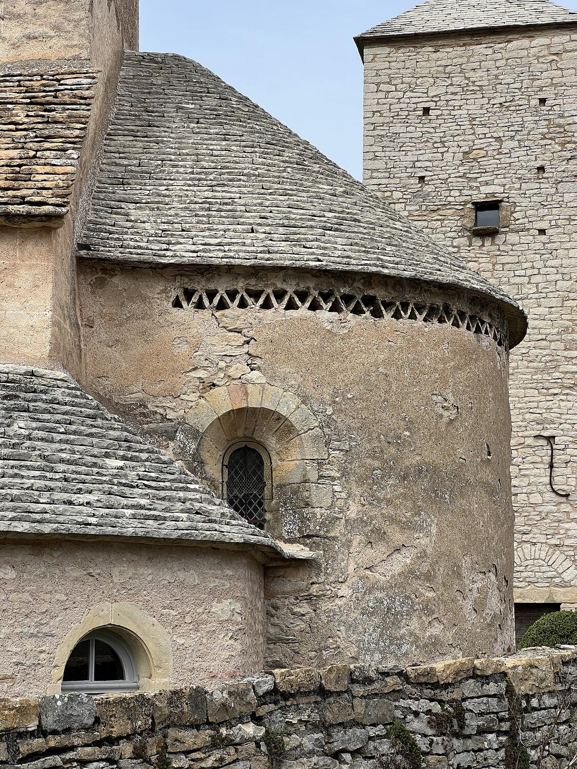 Ábside redondo y torre de la iglesia de Saint-Martin en Blanot, bajo un cielo nublado