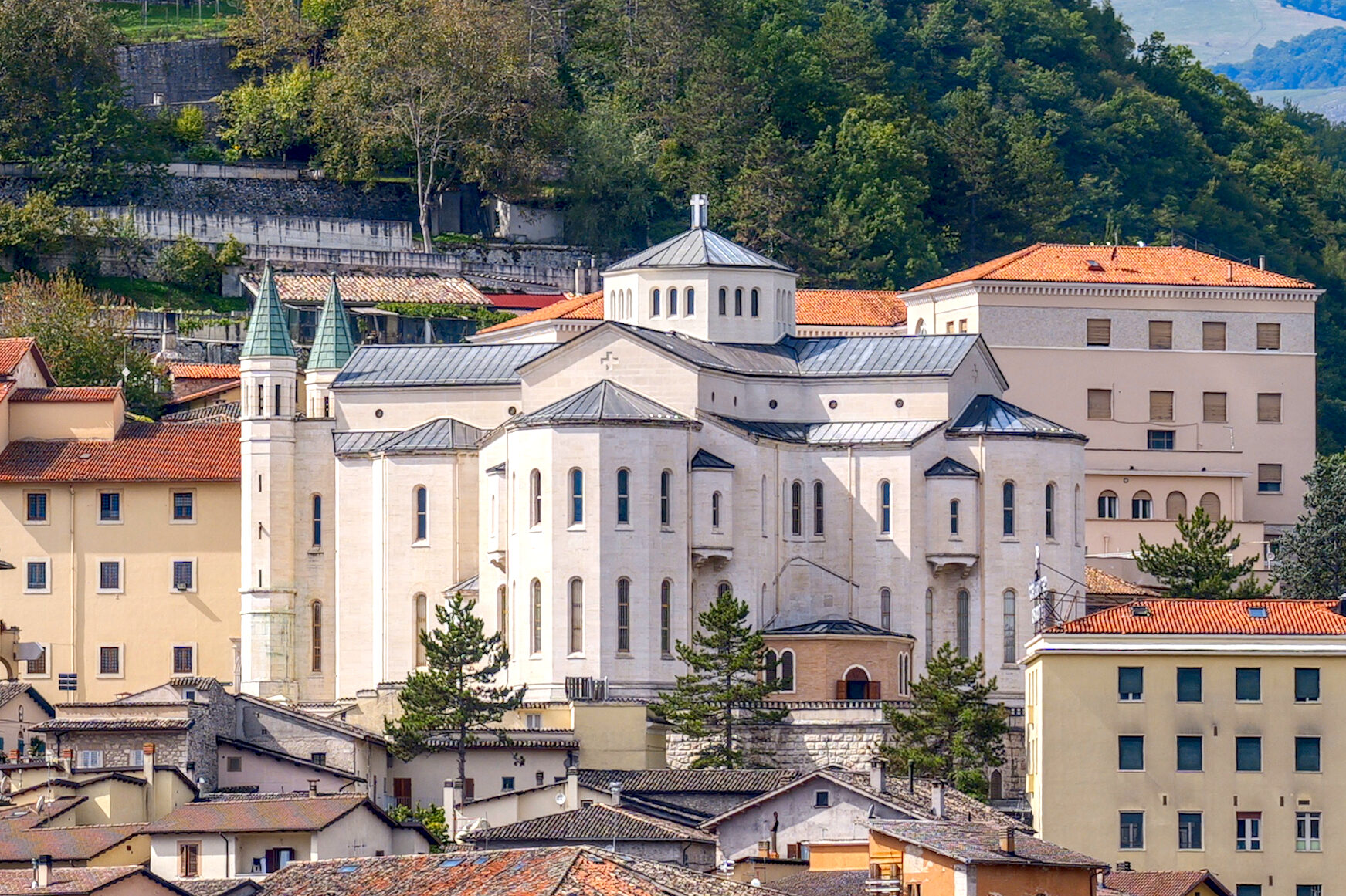 La basílica de Santa Rita de Cascia vista desde lo alto, entre los tejados y los bosques de la montaña de Umbría