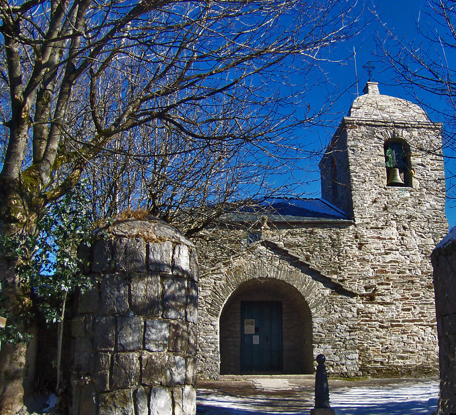 Entrada de la iglesia prerrománica de Santa María a Real de O Cebreiro, con su espadaña y un cielo azul