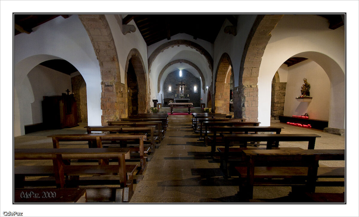 Interior de la iglesia de Santa María a Real de O Cebreiro, con bancos de madera y arcos de piedra