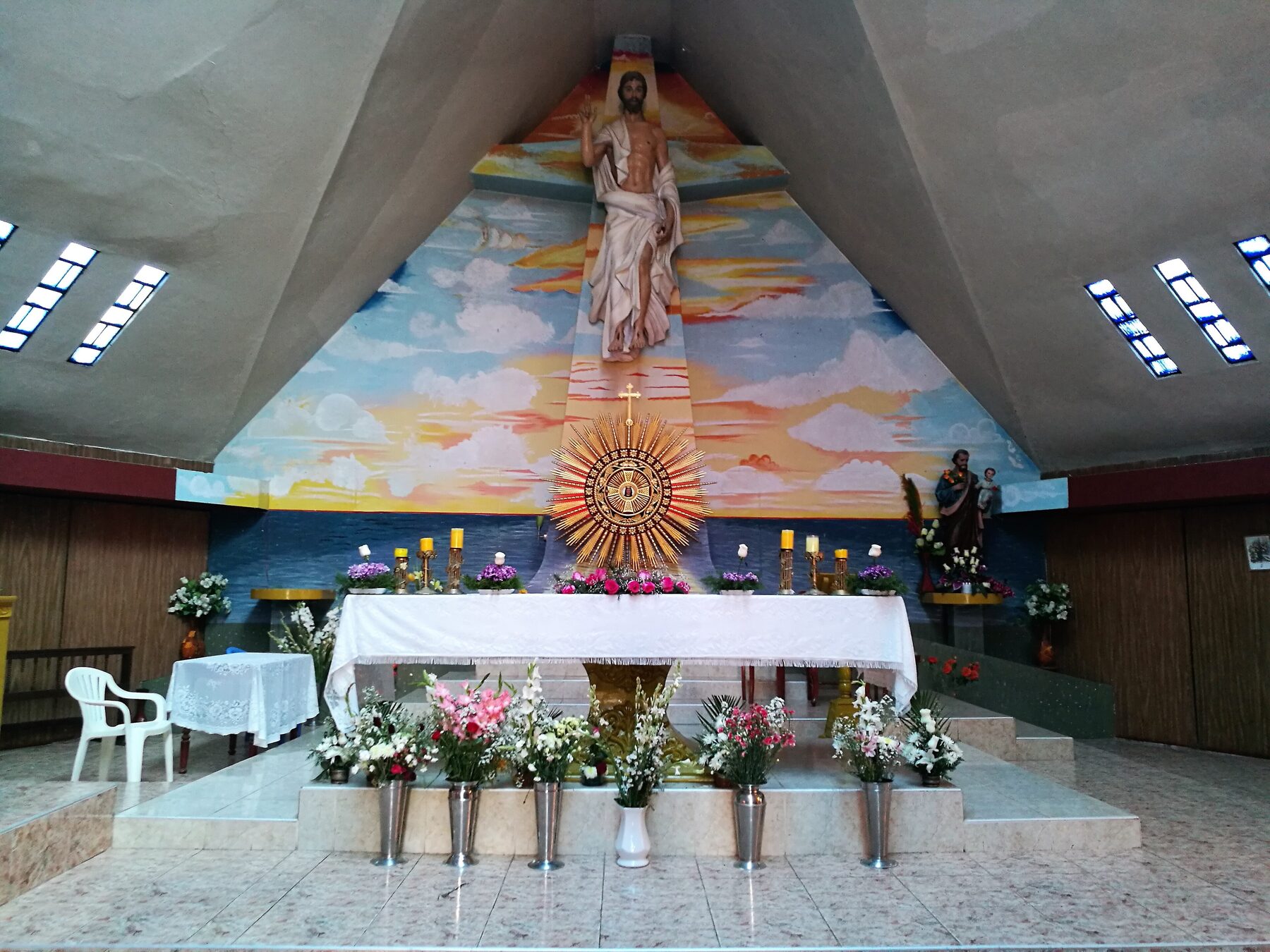 Altar de la iglesia de Santa María Magdalena de Eten, con un mural de Cristo y flores