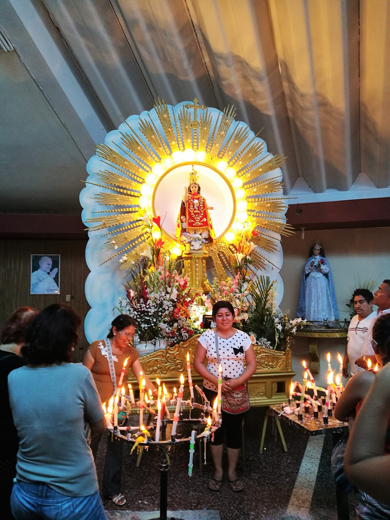 Imagen del Divino Niño del Milagro de Eten rodeada de rayos dorados y de velas encendidas por los devotos