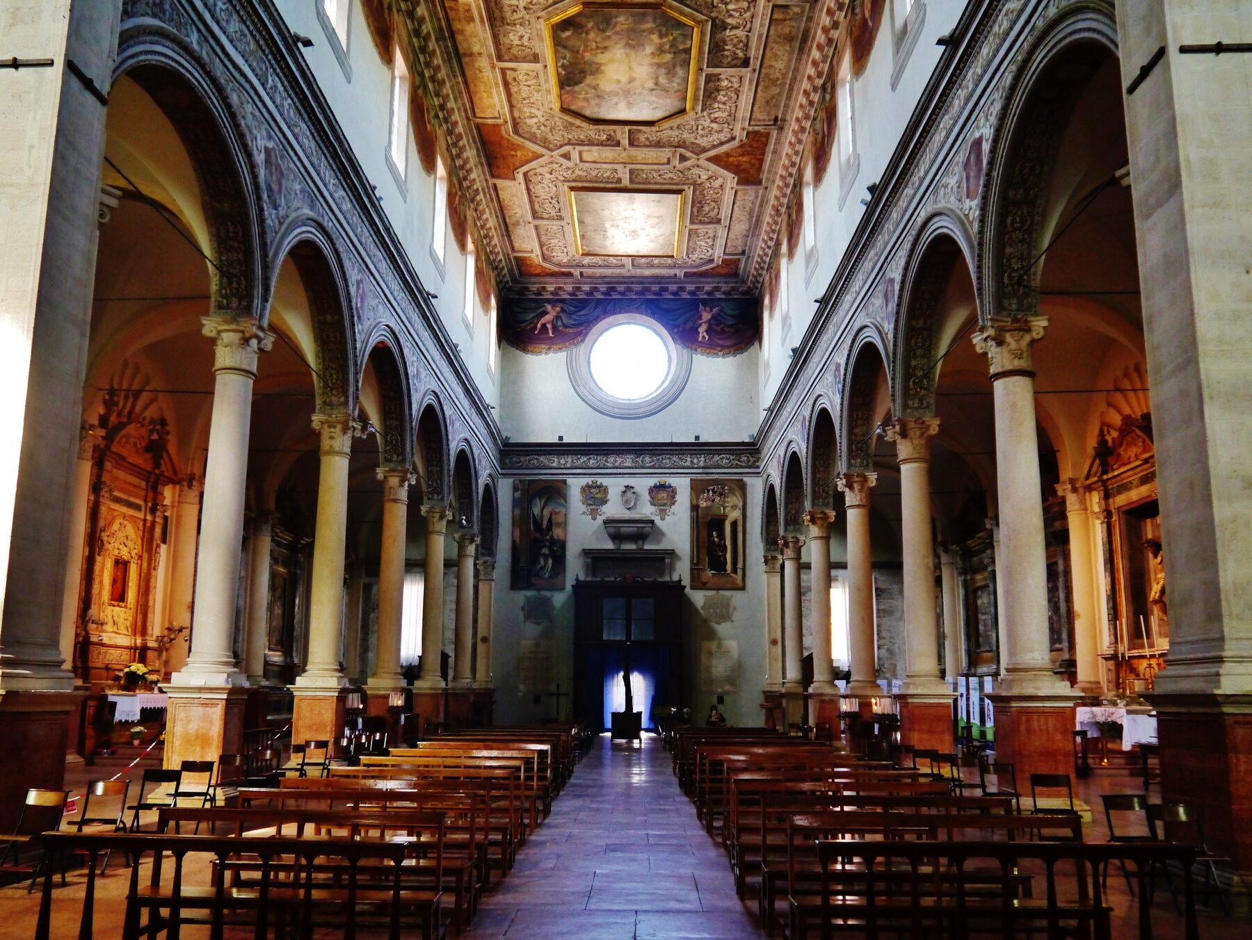 Nave central de la basílica de Santa Maria in Vado de Ferrara, con arcos, columnas y techo decorado, donde se venera el milagro eucarístico de 1171