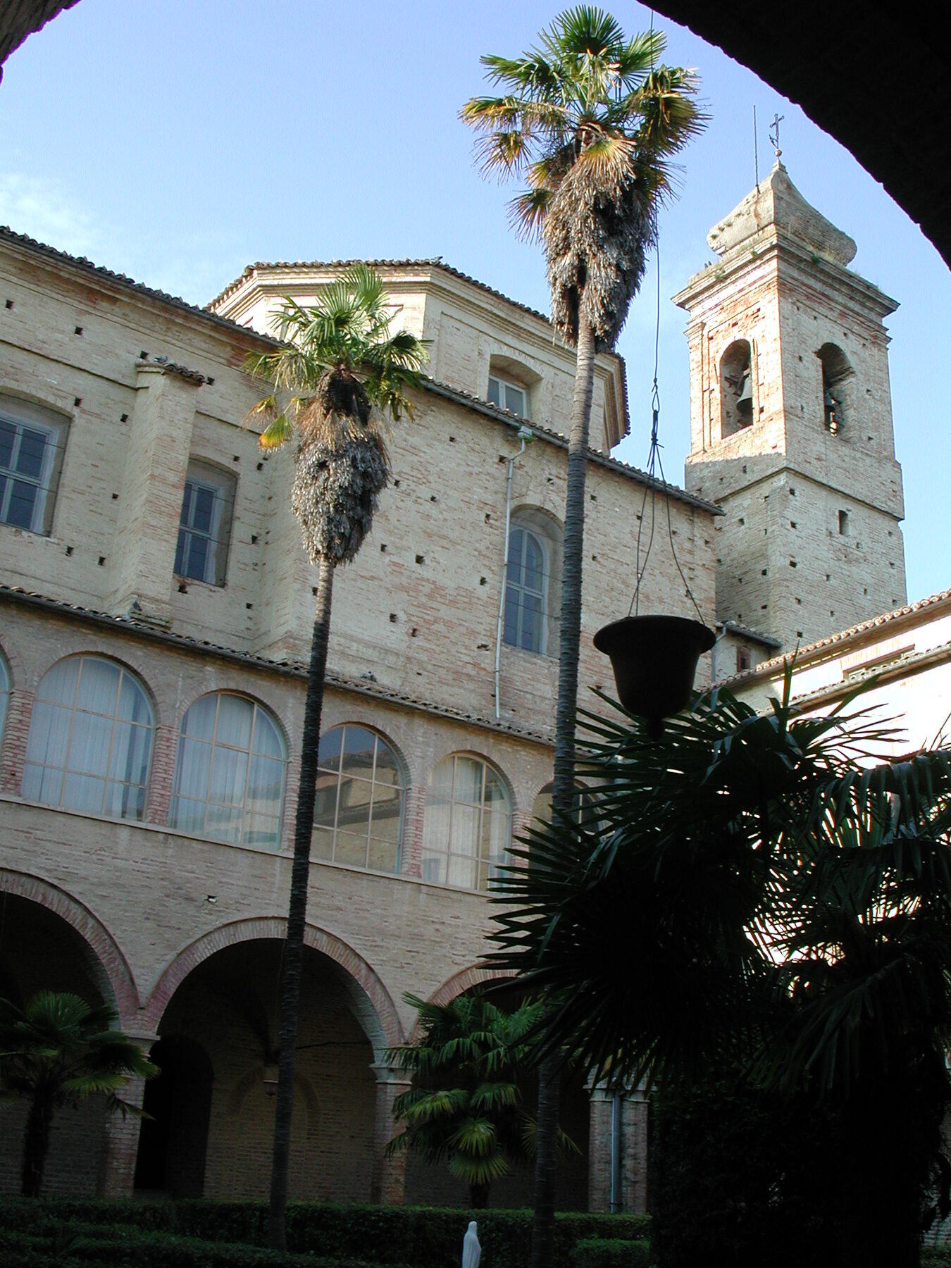 Claustro del antiguo convento agustino de Sant'Agostino en Offida, con arcos y palmeras